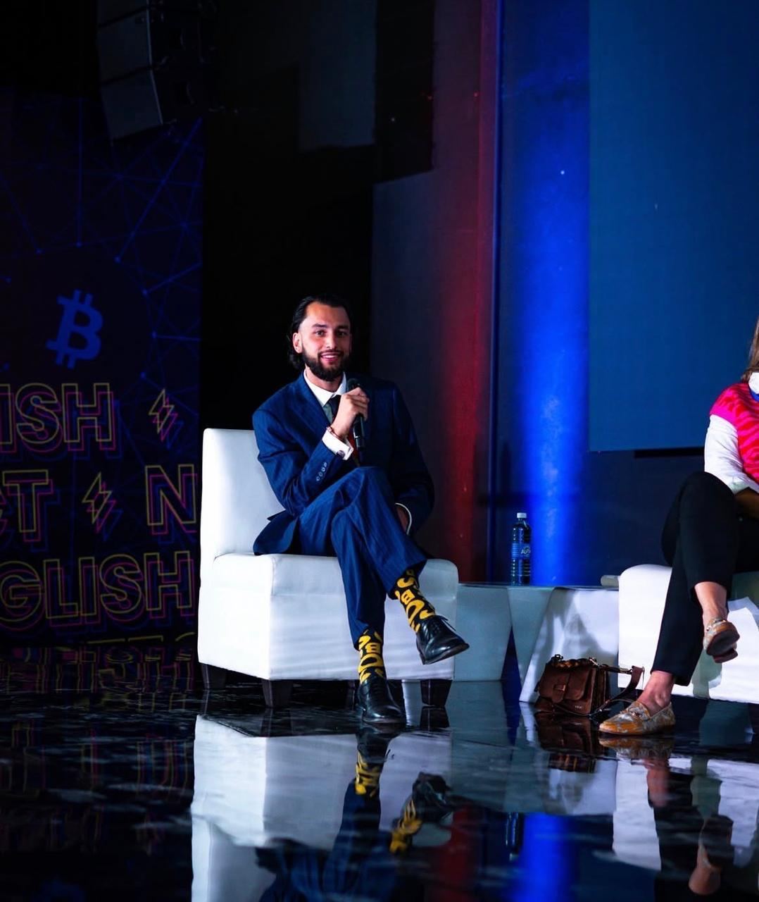 Chris speaking on a panel beside a Bitcoin logo