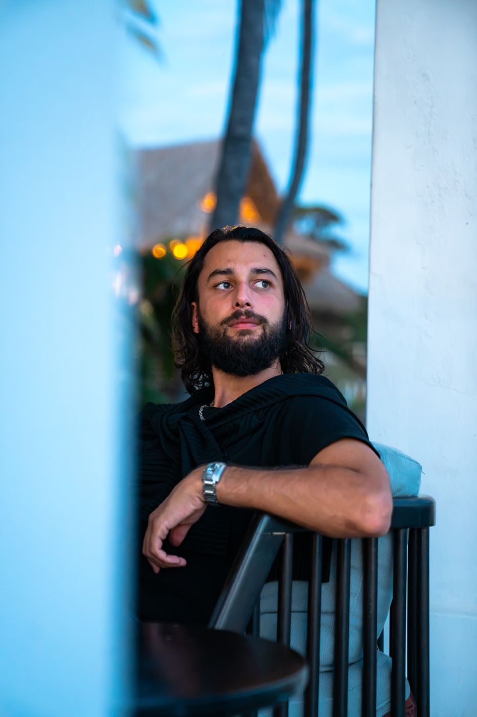 Chris seated on a white terrace on the Pacific coast at dusk