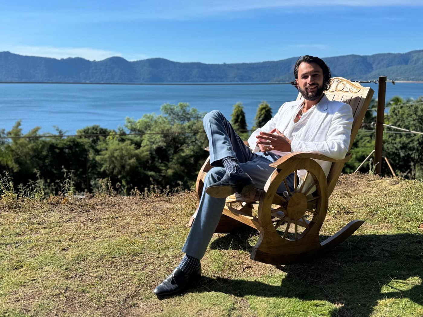 Chris in a white linen jacket in a carved rocking chair above Lake Coatepeque